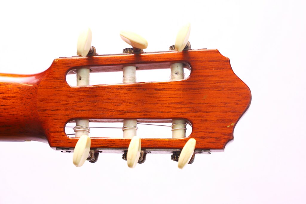 Close-Up Of The Headstock Of A Conde Hermanos 1971 Flamenco Guitar, Featuring Six Tuning Pegs And White Strings Set Against A White Background.