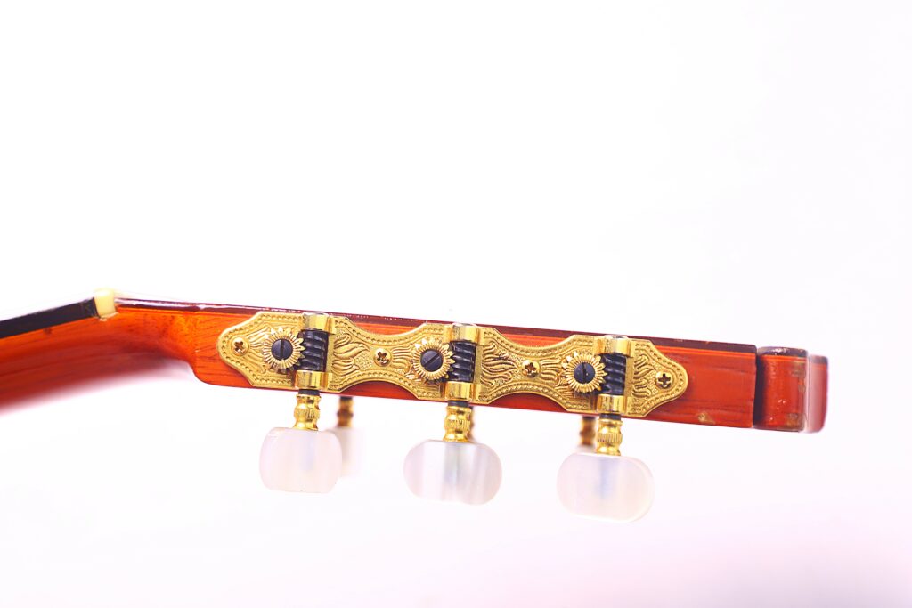 Close-Up Of The Headstock Of A Hermanos Conde 1986 Paco De Lucia Flamenco Guitar, Featuring Three Ornate Gold Tuning Pegs With White Knobs Against A Plain White Background.