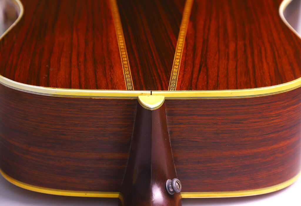 Close-Up Of The Back Of A Martin Hd-35 1979 Acoustic Guitar, Showing Detailed Wood Grain, Decorative Inlays, And Yellow Edge Binding. The Neck Heel And Strap Button Are Also Visible At The Bottom Center.