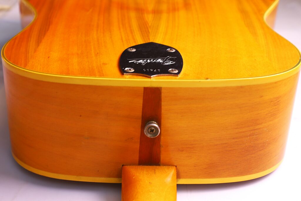 Close-Up Of The Back Of A Fender Wildwood 1967 Acoustic Guitar, Highlighting The Neck Joint, A Metal Bolt, And A Black Plate Engraved With A Signature And The Word Styve.