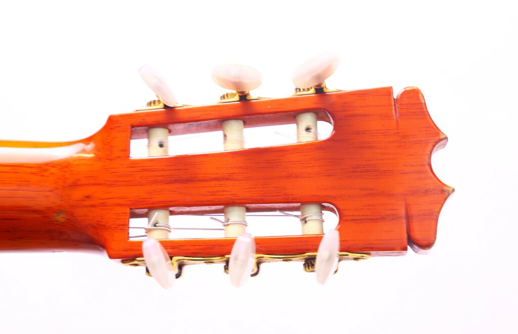 Close-Up Of The Headstock Of A Hermanos Conde 1986 Paco De Lucia Flamenco Guitar With White Tuning Pegs And Nylon Strings Against A White Background.