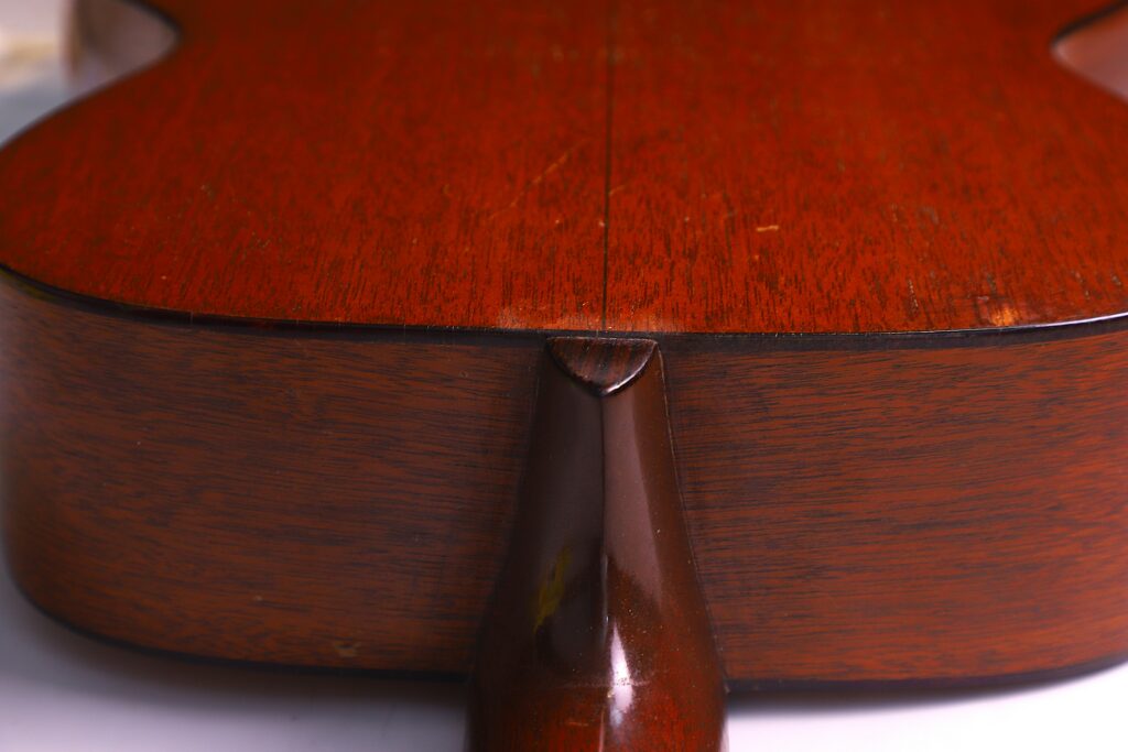 Close-Up Of The Back And Neck Joint Of A Martin 000-18 1950 Acoustic Guitar, Highlighting The Smooth Reddish-Brown Wood Grain And The Seam Where The Two Halves Of The Back Meet.