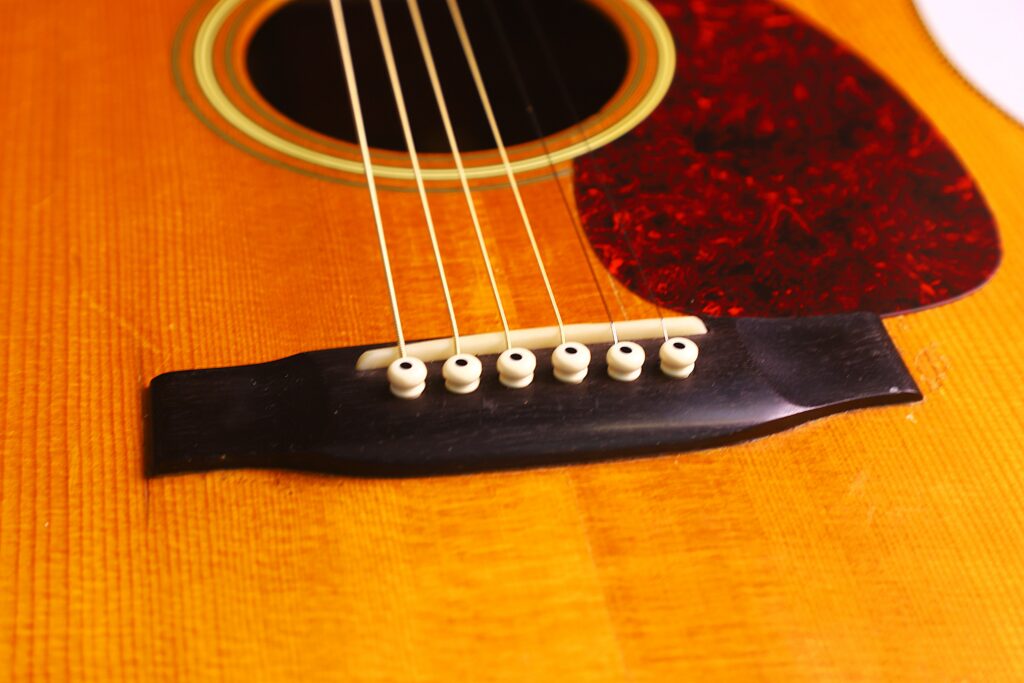 Close-Up Of The Martin Hd-35 1979 Acoustic Guitars Strings, Bridge, And Pickguard, Highlighting The Wood Grain And Detailed Texture Of The Instrument’s Body.
