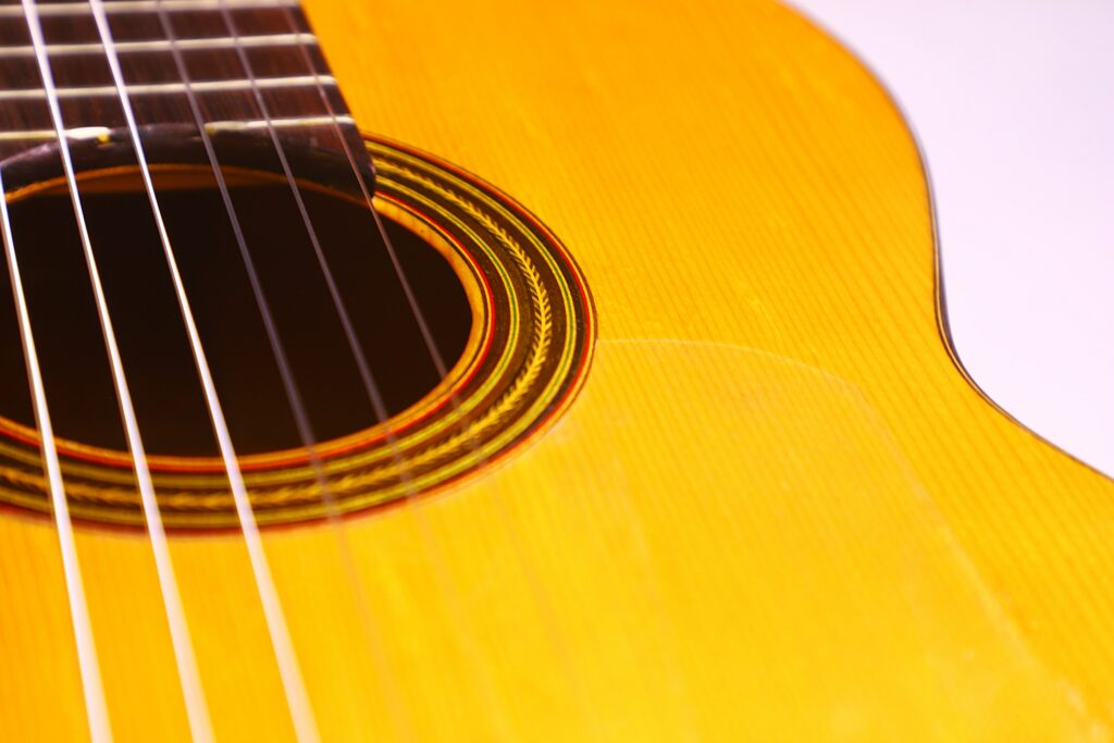 Close-Up Of A Conde Hermanos 1971 Flamenco Guitar Body, Highlighting The Strings, Decorative Rosette Around The Soundhole, And Part Of The Warm Yellow-Finished Wooden Top.