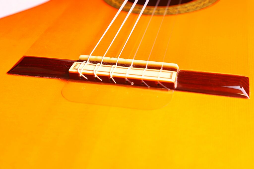 Close-Up Of The Bridge And Strings Of A Hermanos Conde 1986 Paco De Lucia Flamenco Guitar, Highlighting Its Yellow-Toned Wooden Body And Part Of The Sound Hole At The Top.
