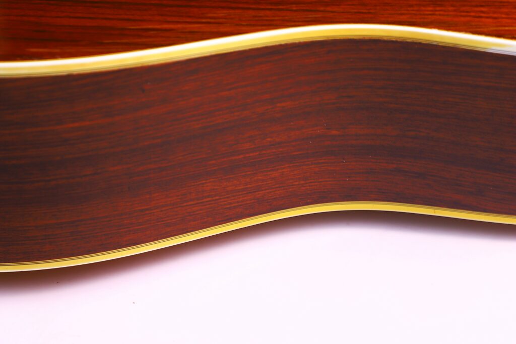 Close-Up Of The Side Of A Martin Hd-35 1979 Acoustic Guitar, Featuring Detailed Wood Grain, A Glossy Finish, And Light Binding On The Edge, Set Against A White Background At The Bottom.