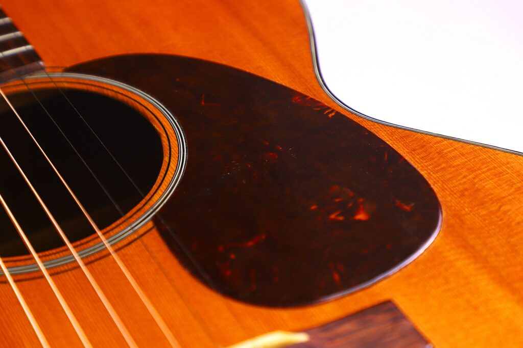 Close-Up Of A Martin 000-18 1950 Acoustic Guitar, Highlighting Its Strings, Sound Hole, Pickguard, And Part Of The Wooden Body With A Warm Brown Finish.