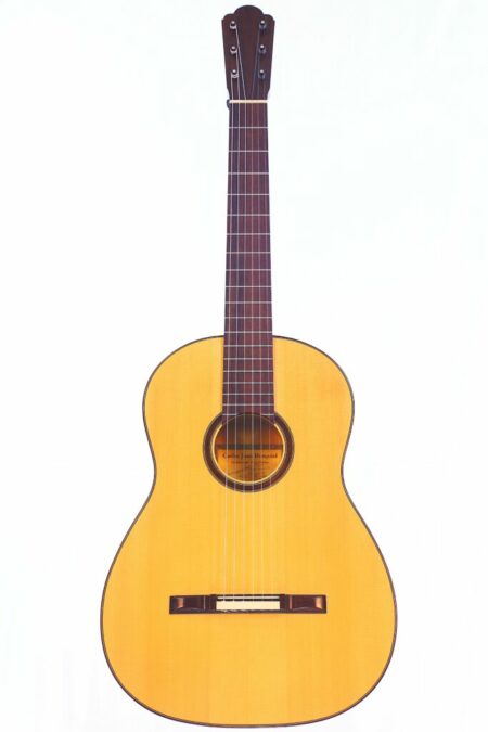 The Carlos Juan Busquiel 2015 Torres Classical Guitar features a natural wood finish, dark brown fretboard, and round sound hole, shown against a plain white background.