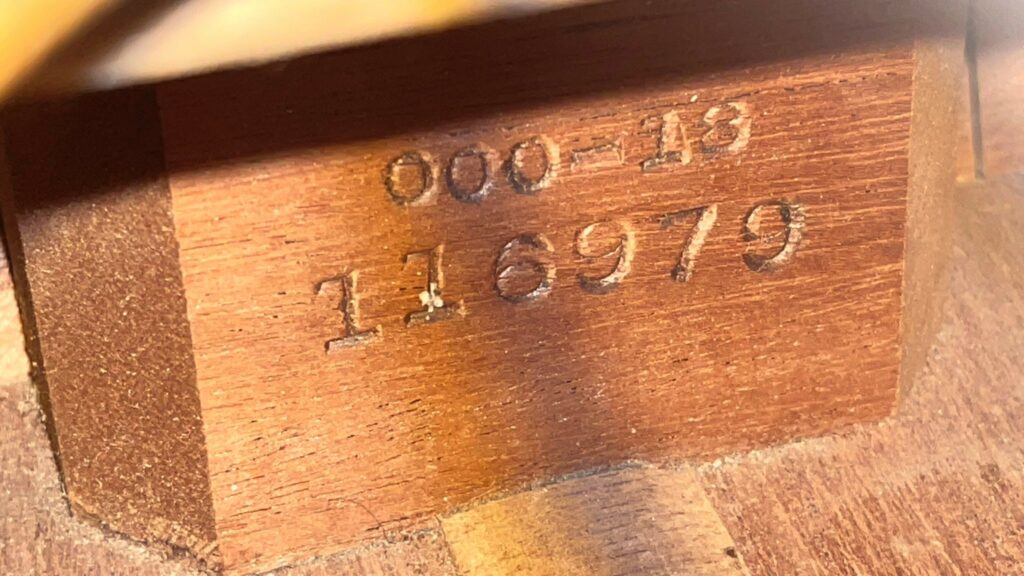 Close-Up Of A Martin 000-18 1950 Acoustic Guitars Warm Brown Wood, Displaying Engraved Serial Number 116979 And Model Number 000-18.