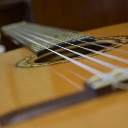 Close-Up View Of The Strings And Sound Hole Of An Acoustic Guitar, With A Shallow Depth Of Field Creating A Blurred Background.