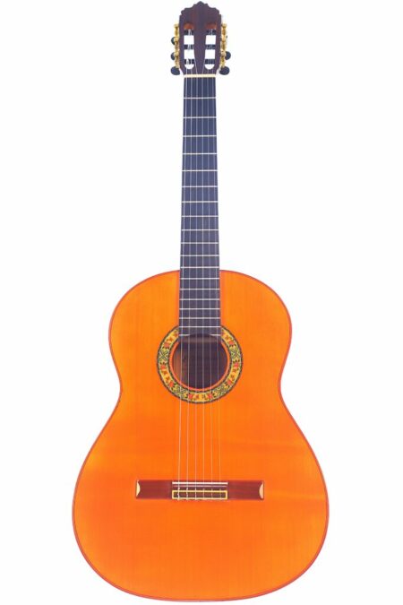 The Emilio Fernandez 2019 Negra Flamenco Guitar features nylon strings, a glossy orange-brown finish, and a decorative rosette, shown against a white background.
