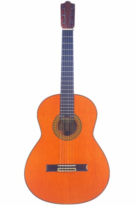 The Manuel Caceres 1984 Flamenco Guitar, featuring a wooden body and six strings, is displayed upright against a white background.