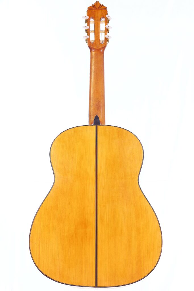 A Gerundino Fernandez 1990 Flamenco Guitar Displayed From The Back, Showcasing A Light Wood Finish With A Dark Vertical Central Stripe And A Wooden Neck With Tuning Pegs.