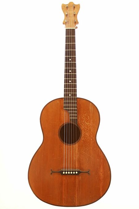 The Classical Guitar 1900 Markneukirchen features a wooden body, six strings, and a dark fingerboard with visible wear, indicating frequent use. It is shown against a plain white background.
