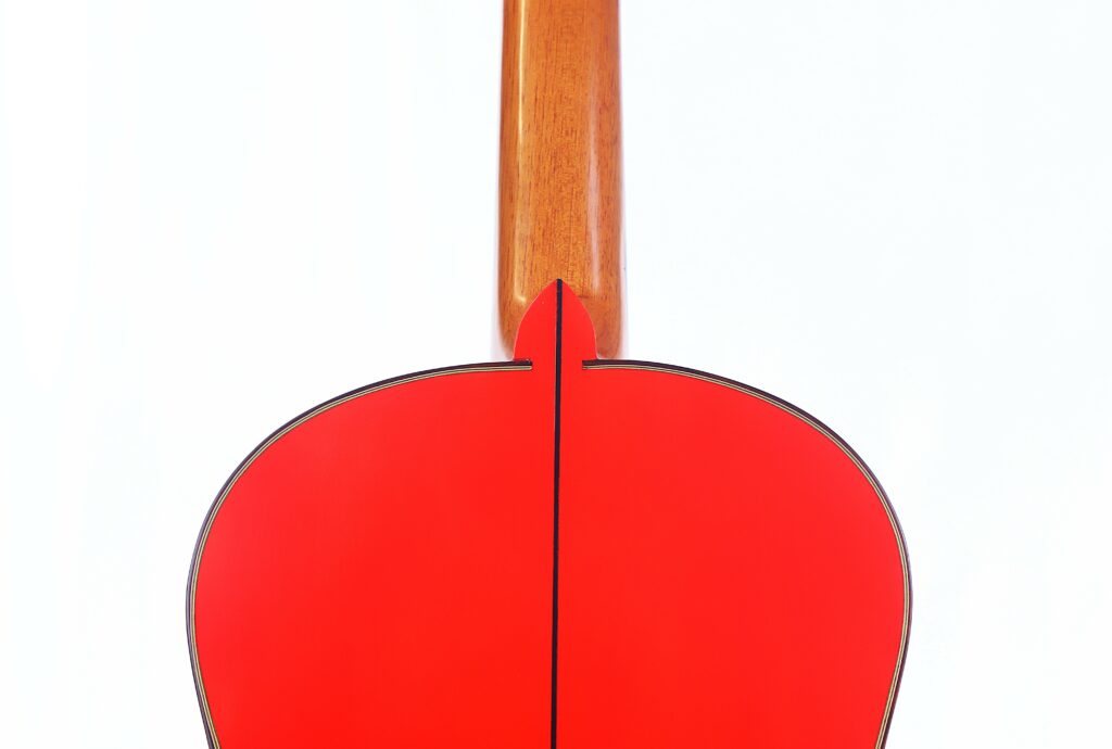 Close-Up Of The Pedro Fernández Luque 2021 Blanca Flamenco Guitar'S Back, Showing Its Red Body And Natural Wood Neck Against A Plain White Background.