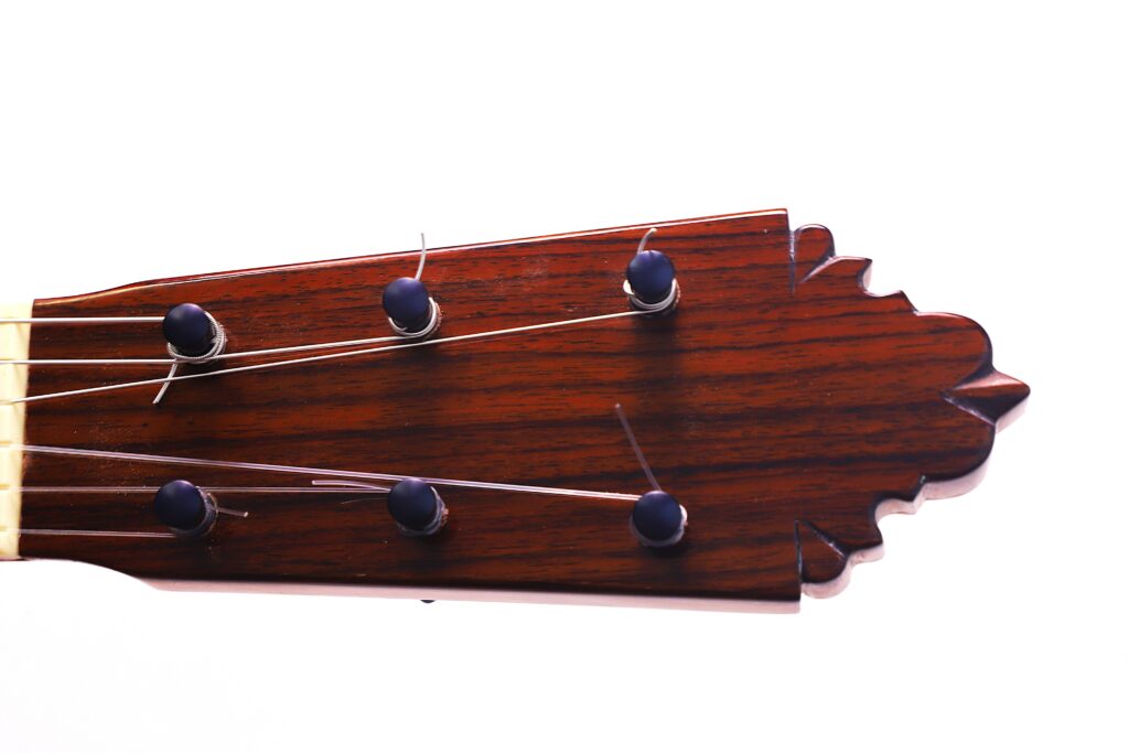 Close-Up Of The Pedro Fernández Luque 2021 Blanca Flamenco Guitar Headstock, Featuring Five Tuning Pegs, Metal Strings, And A Carved Decorative Edge On A White Background.