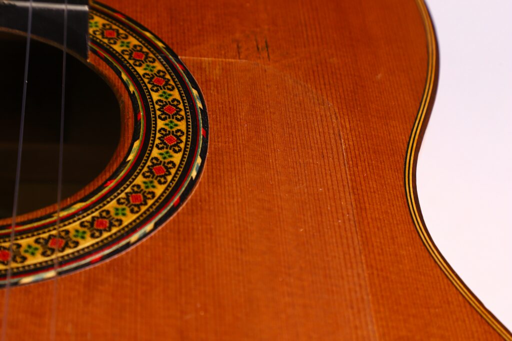 Close-Up Of The Gerundino Fernandez 1990 Flamenco Guitar’s Body, Showing The Intricate Rosette Around The Sound Hole, Detailed Wood Grain, And Guitar Strings Visible Along The Left Edge.