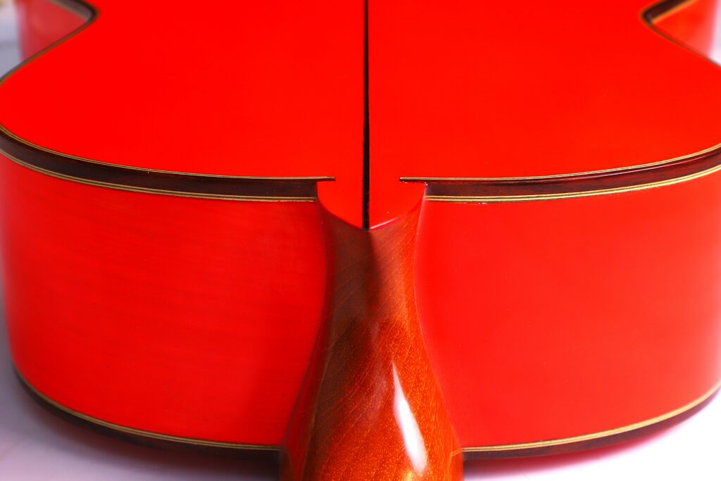 Close-Up View Of The Back And Neck Of The Pedro Fernández Luque 2021 Blanca Flamenco Guitar, Highlighting Its Bright Red Hue, Glossy Wooden Finish, And Intricate Craftsmanship.