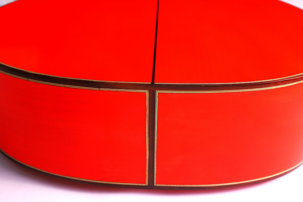 Close-Up Of A Shiny, Round Red Object With Thin Gold Trim And Visible Seams, Showcasing Craftsmanship Like That Of The Pedro Fernández Luque 2021 Blanca Flamenco Guitar, Set Against A White Background.