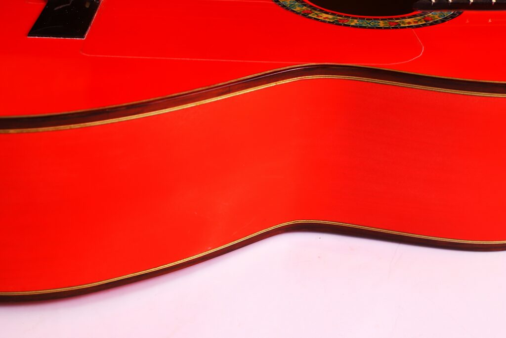 A Close-Up Of The Pedro Fernández Luque 2021 Blanca Flamenco Guitar Reveals Its Curved Body, Decorative Edge, And Part Of The Sound Hole, Set Against A White Background.
