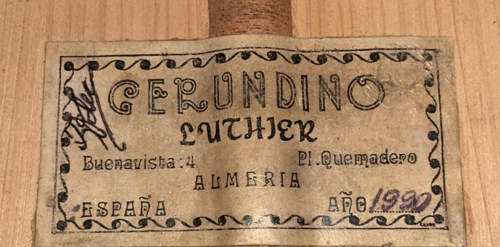 A Label Reading “Gerundino Luthier,” With The Address “Buenavista: 4, Pl. Quemadero, Almeria, España” And “Año 1980” In Purple Ink, Is Attached To The Wood Of A Gerundino Fernandez 1990 Flamenco Guitar.
