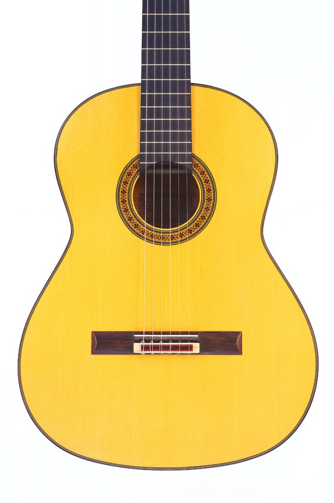 Die Manuel Reyes 1991 Flamenco-Gitarre Verfügt Über Einen Hellen Holzkorpus, Ein Dunkles Griffbrett Und Eine Komplizierte Rosette Um Das Schallloch, Die Auf Einem Weißen Hintergrund Präsentiert Wird.
