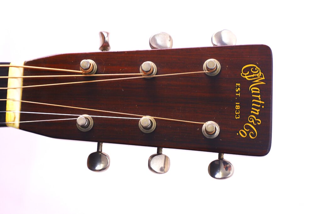 Nahaufnahme Der Kopfplatte Der Martin D-28 1950 Akustik Gitarre, Mit Sechs Stimmwirbeln, Gelbem C.f. Martin &Amp; Co. Est. 1833 Logo Auf Dunklem Holz Und Sichtbaren Gitarrensaiten Vor Einem Weißen Hintergrund.