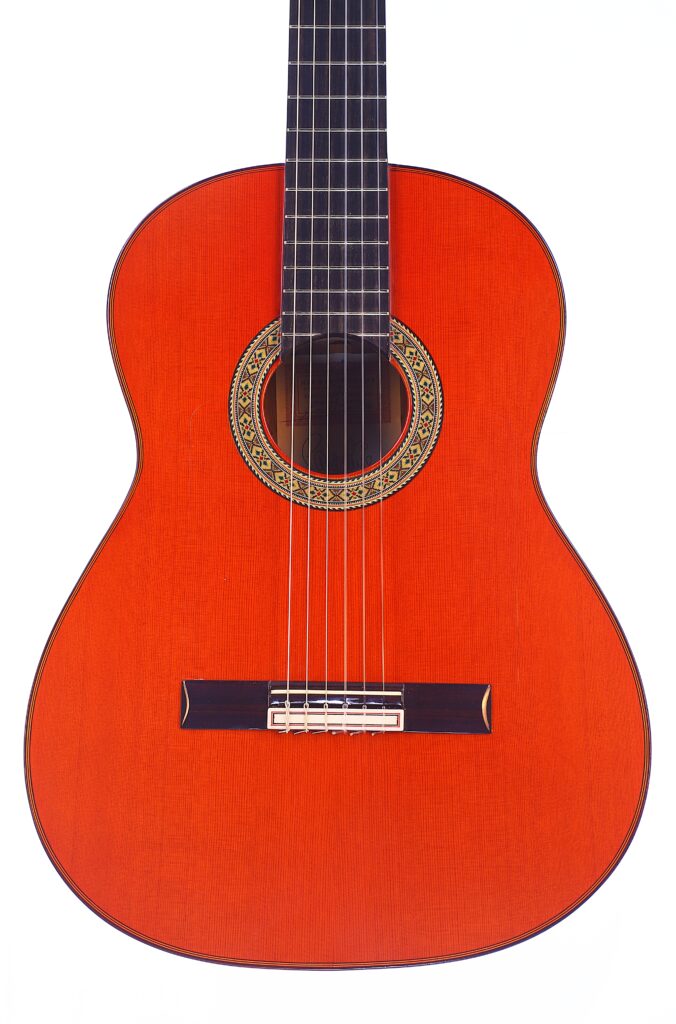 Die Hermanos Conde 1991 Paco De Lucia Special Flamenco Gitarre Zeichnet Sich Durch Einen Hellen, Rötlich-Orangenfarbenen Korpus, Filigrane Rosettendetails Und Einen Schwarzen Steg Aus, Die Vor Einem Weißen Hintergrund Gezeigt Werden.