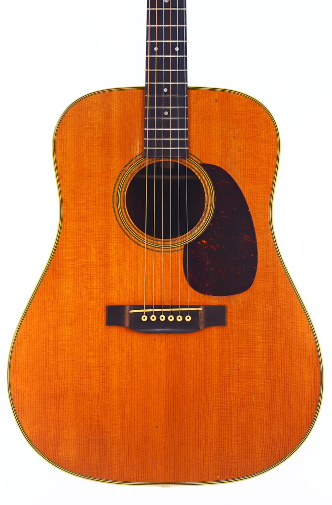 Nahaufnahme Einer Martin D-28 1950 Akustik Gitarre Mit Einem Natürlichen Holzfinish, Schwarzem Schlagbrett, Sechs Saiten Und Punkt-Inlays Auf Dem Griffbrett, Fotografiert Vor Einem Weißen Hintergrund.