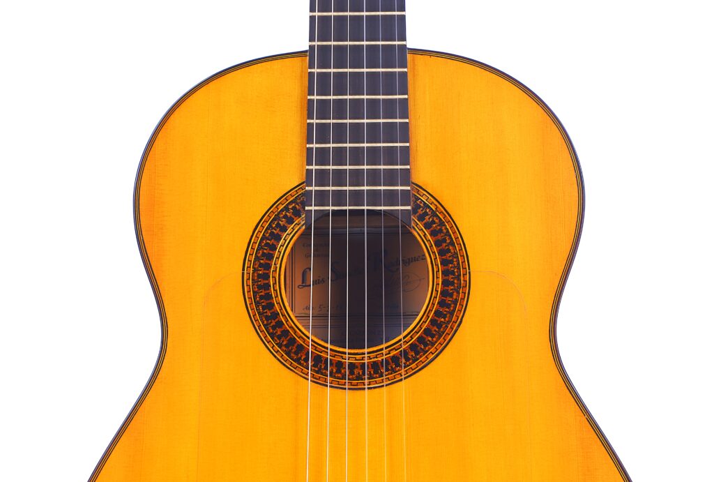 Nahaufnahme Des Korpus Und Des Halses Einer Luis Sanchez 2011 Negra Flamenco Gitarre, Die Ihre Hölzerne Decke, Die Dekorative Rosette Um Das Schallloch Und Die Nylonsaiten Hervorhebt.