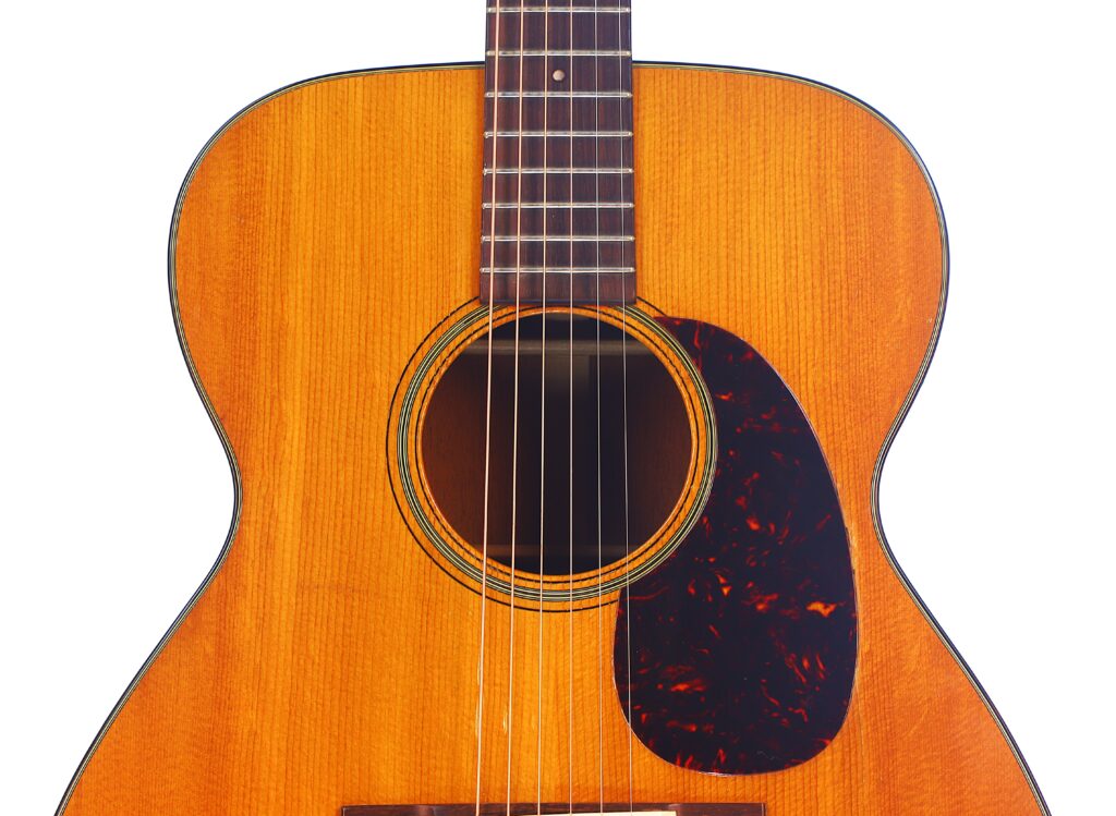 Nahaufnahme Von Korpus Und Hals Einer Martin 000-18 1958 Akustik Gitarre, Mit Einem Hellbraunen Holz-Finish Und Einem Dunklen Marmorierten Schlagbrett.