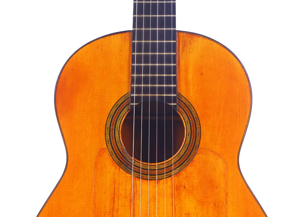 Santos Hernandez 1930 弗拉明戈吉他琴身和下颈特写,白色背景下的木质琴面显示出音孔、琴弦和部分指板。.