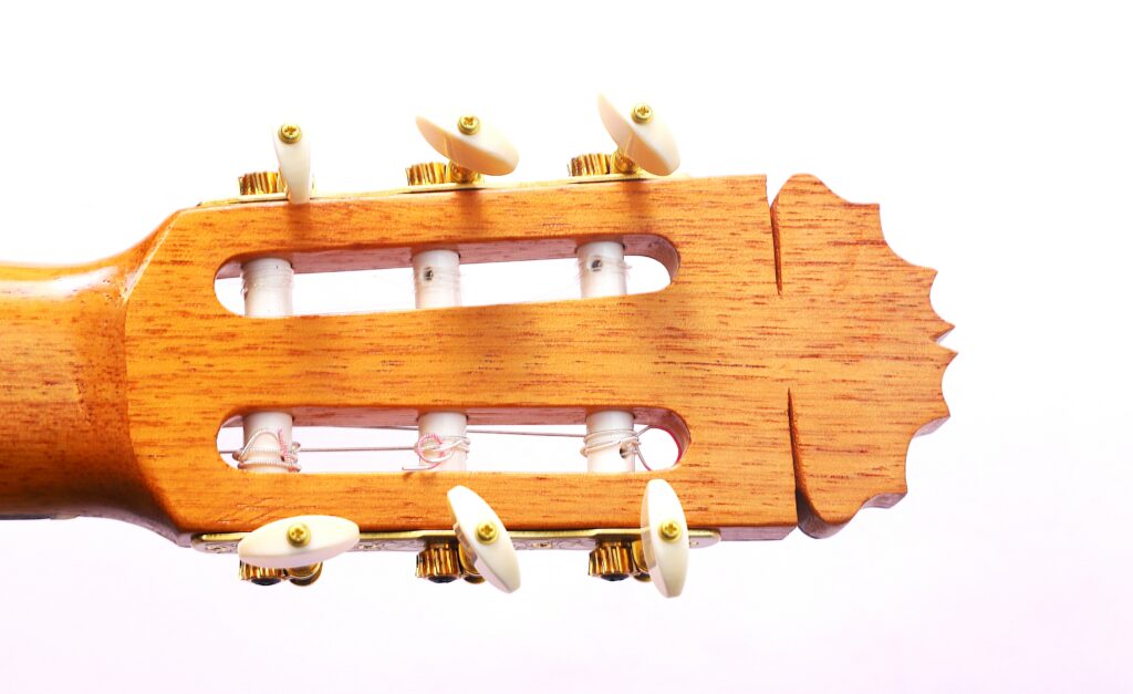 Nahaufnahme Der Stimmwirbel Und Der Kopfplatte Einer Manuel Reyes Flamenco-Gitarre Von 1991 Mit Weißen Stimmschlüsseln Und Goldener Hardware Auf Einem Hellen Holzhintergrund.