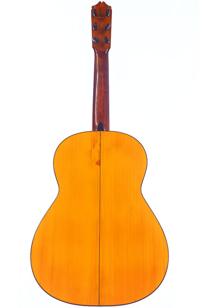 图片展示的是 Santos Hernandez 1930 弗拉门戈吉他的背面,突出了其闪亮的木质表面和天然纹理,白色背景下的琴颈清晰可见。.