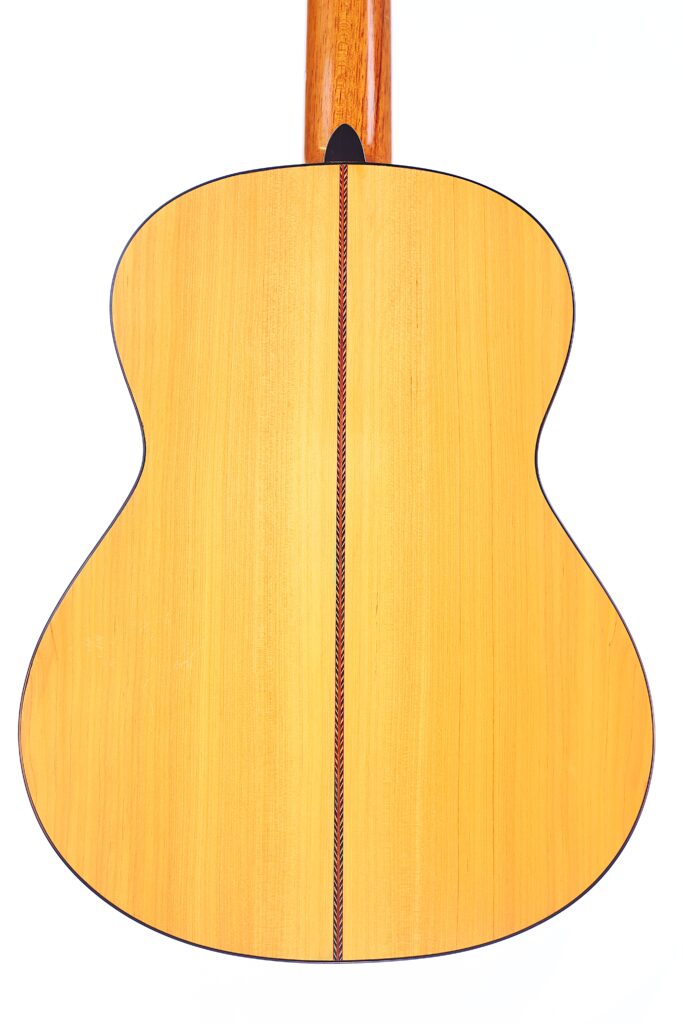 Das Bild Zeigt Die Rückseite Einer Manuel Reyes Model 2021 Von Hippner Flamenco Gitarre, Mit Hellem Holz, Einer Dunklen Vertikalen Einlage Entlang Der Mittelfuge, Einer Geschwungenen Körperform Und Einem Hölzernen Hals.