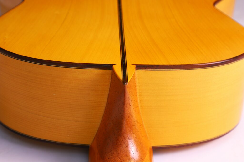 Nahaufnahme Des Rücken- Und Halsgelenks Einer Manuel Reyes Flamenco-Gitarre Aus Dem Jahr 1991, Die Das Glatte, Polierte Holz Mit Warmen, Natürlichen Tönen Und Detaillierter Verarbeitung Hervorhebt.