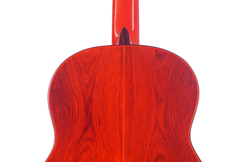 Nahaufnahme Der Glänzenden, Rötlich-Braunen Rückseite Einer Hermanos Conde 1991 Paco De Lucia Special Flamenco Gitarre, Die Die Holzmaserung Und Die Mittelfuge Vor Einem Weißen Hintergrund Zeigt.