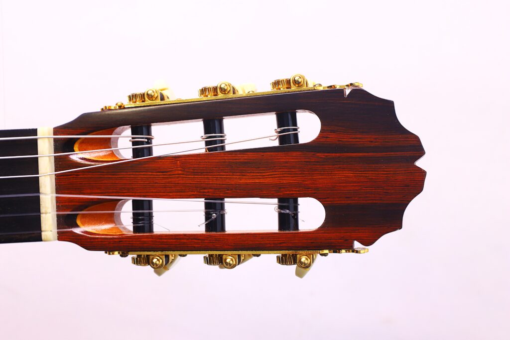 Nahaufnahme Der Kopfplatte Der Manuel Reyes Model 2021 Von Hippner Flamenco Gitarre Mit Goldenen Stimmwirbeln Und Einem Dunklen Holzfinish, Vor Einem Schlichten Weißen Hintergrund.