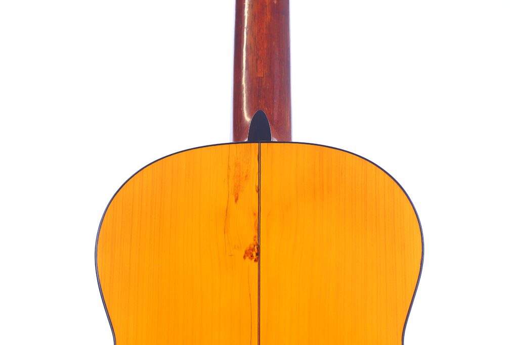 Santos Hernandez 1930 弗拉门戈吉他背面特写,在白色背景衬托下,凸显其光亮的橙色木质表面和中央接缝。.