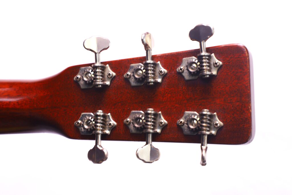 Nahaufnahme Der Rückseite Einer Martin 000-18 1958 Akustik Gitarren-Kopfplatte, Die Sechs Metallene Stimmwirbel An Einem Holzhals Vor Einem Weißen Hintergrund Zeigt.