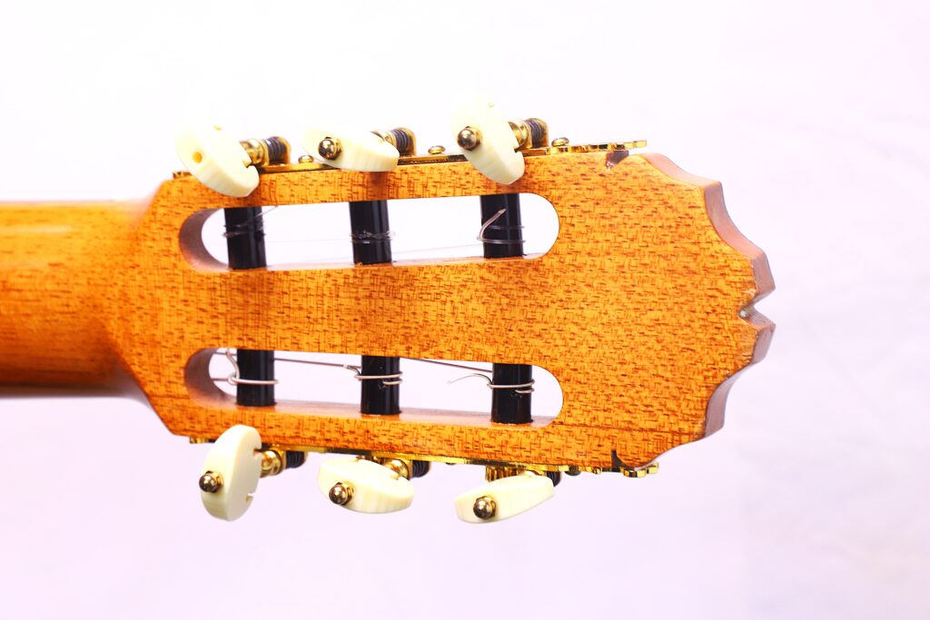 Nahaufnahme Der Kopfplatte Der Manuel Reyes Model 2021 Von Hippner Flamenco Gitarre, Mit Sechs Weißen Stimmwirbeln Und Goldener Hardware Auf Einem Hölzernen Hals, Vor Einem Schlichten Weißen Hintergrund.
