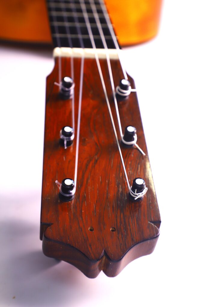 Santos Hernandez 1930 年弗拉门戈吉他琴头特写,白色背景下显示出六个音栓和琴弦,部分琴颈和琴身清晰可见。.