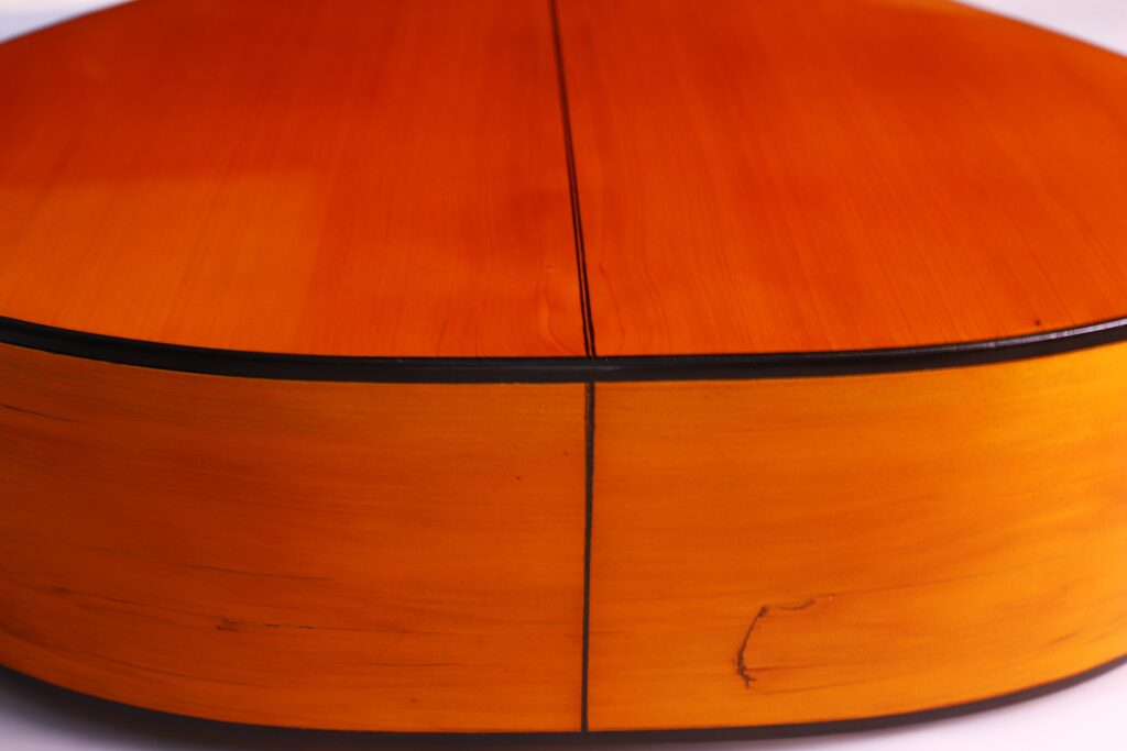 Santos Hernandez 1930 年弗拉门戈吉他背面和侧面特写,突出其光滑、抛光的木质表面、明显的中缝和深色边饰。.