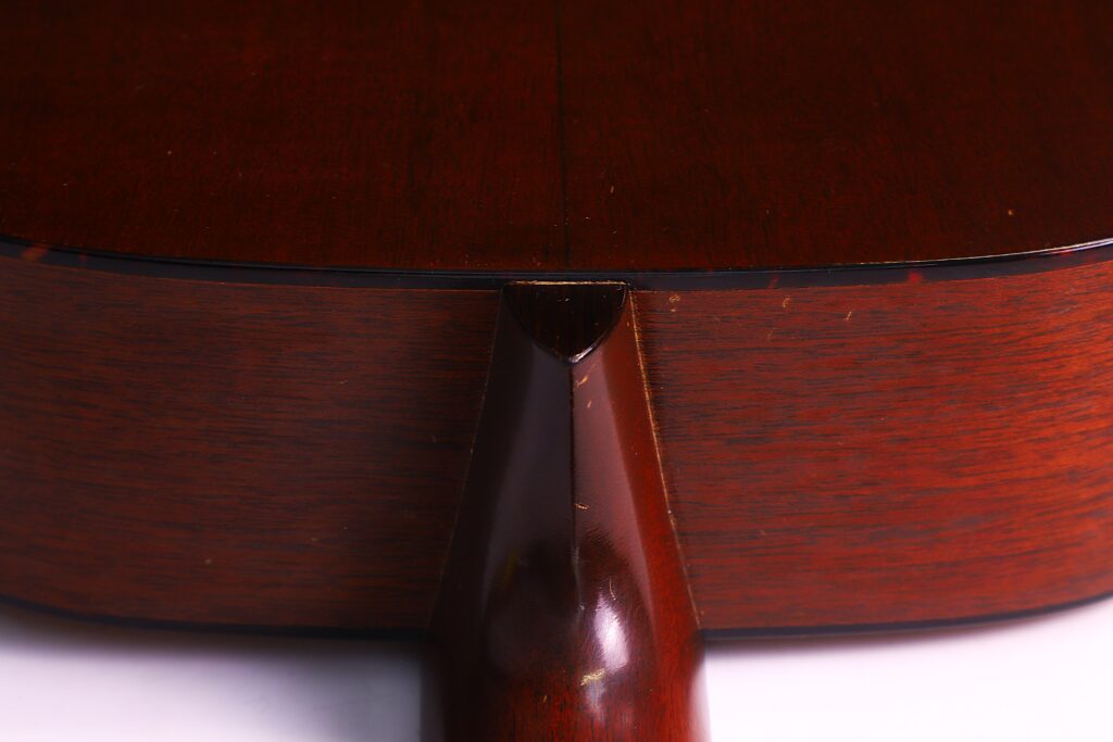 Nahaufnahme Der Rückseite Und Des Halsansatzes Einer Martin 000-18 1958 Akustik Gitarre, Die Die Dunkle Holzmaserung Und Die Polierte Oberfläche Hervorhebt, Wo Der Hals Auf Den Korpus Trifft.