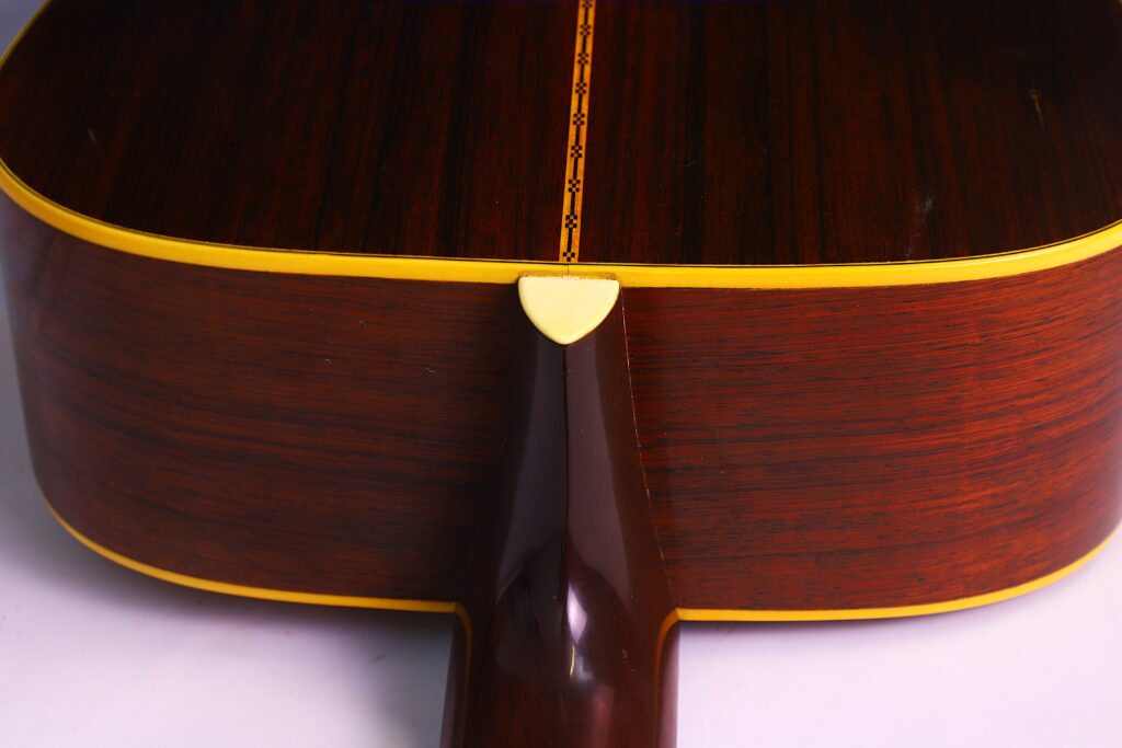 Nahaufnahme Der Rückseite Und Seite Der Martin D-28 1950 Akustik Gitarre, Mit Dunklem Holz, Gelber Zierleiste Und Dekorativer Einlage An Der Naht. Der Hals Trifft Den Korpus In Der Bildmitte.