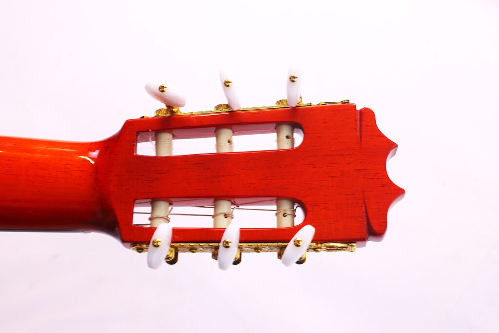 Nahaufnahme Der Kopfplatte Einer Hermanos Conde 1991 Paco De Lucia Special Flamenco Gitarre Mit Roter Holzoberfläche, Weißen Stimmwirbeln Und Goldenen Stimmmechaniken Vor Einem Schlichten Weißen Hintergrund.