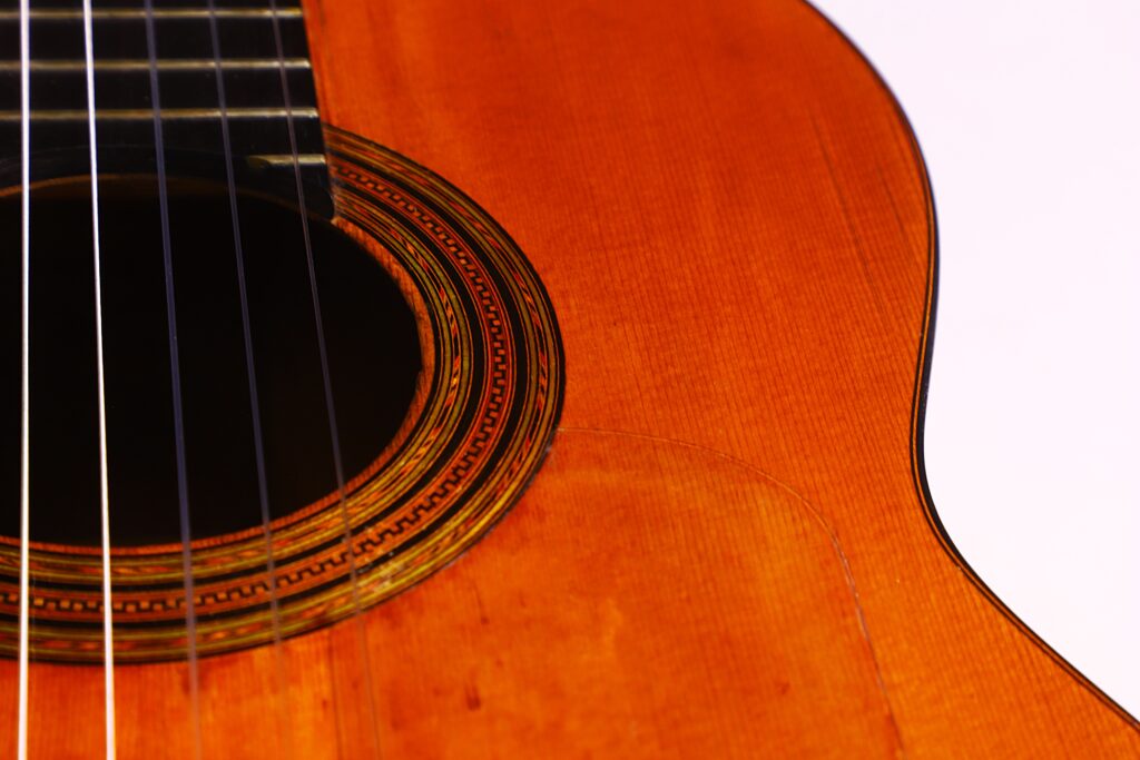 Santos Hernandez 1930 弗拉门戈吉他特写,白色背景下突出音孔、装饰板、琴弦和部分木制琴身。.