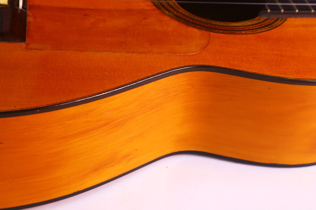 Santos Hernandez 1930 弗拉门戈吉他琴身特写,突出木纹、弧形边缘和部分音孔,背景为白色。.