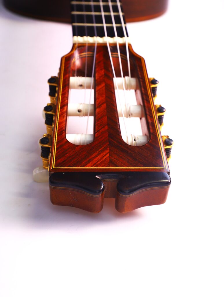 Nahaufnahme Der Kopfplatte Der Luis Sanchez 2011 Negra Flamenco Gitarre, Die Eine Filigrane Holzmaserung, Sechs Stimmwirbel Und Weiße Nylonsaiten Vor Einem Weißen Hintergrund Zeigt.