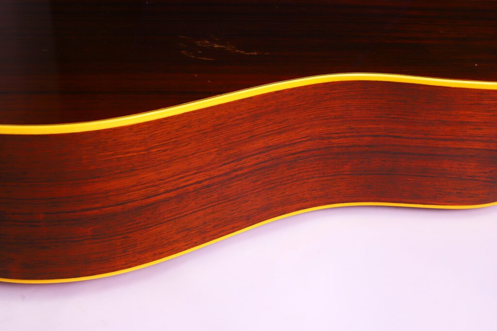 Nahaufnahme Der Martin D-28 1950 Akustik Gitarre, Die Ihre Natürliche Holzmaserung Und Gelbe Einfassung Vor Einem Hellen Hintergrund Zeigt.